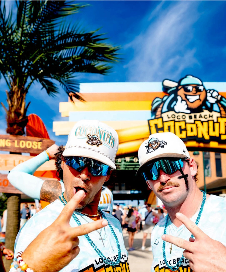 Two ballplayers throwing peace signs at the Coconuts arch